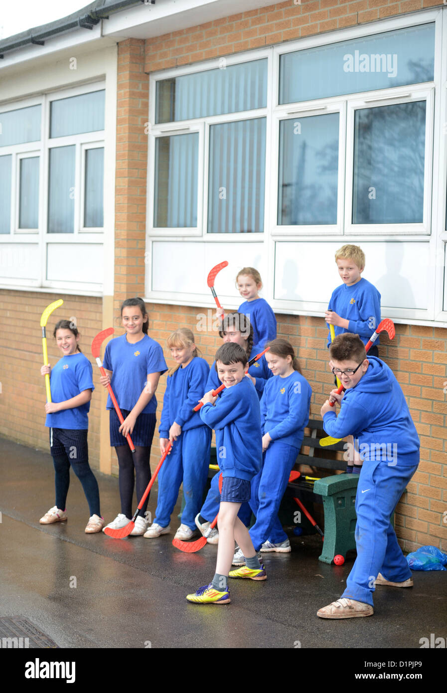 Schoolchildren wait for the rain to stop before starting hockey practice at Our Lady & St. Werburgh's Catholic Primary School in Stock Photo