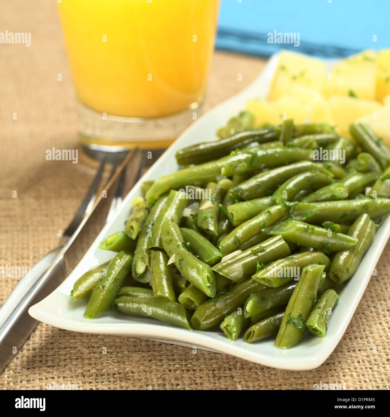 Cooked green beans with onion and parsley with cooked potato, orange ...