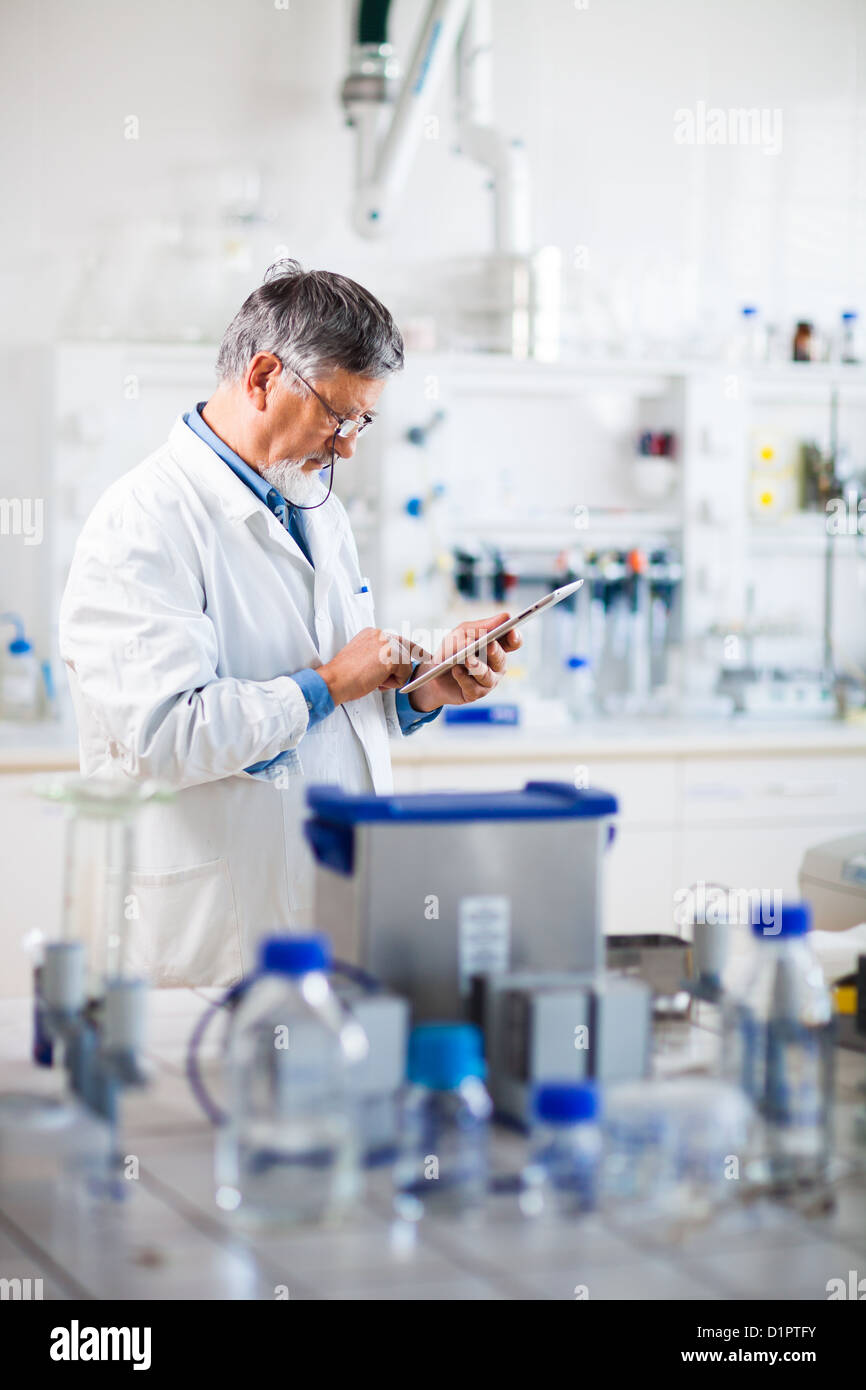 Senior doctor/scientist using his tablet computer at work (color toned ...