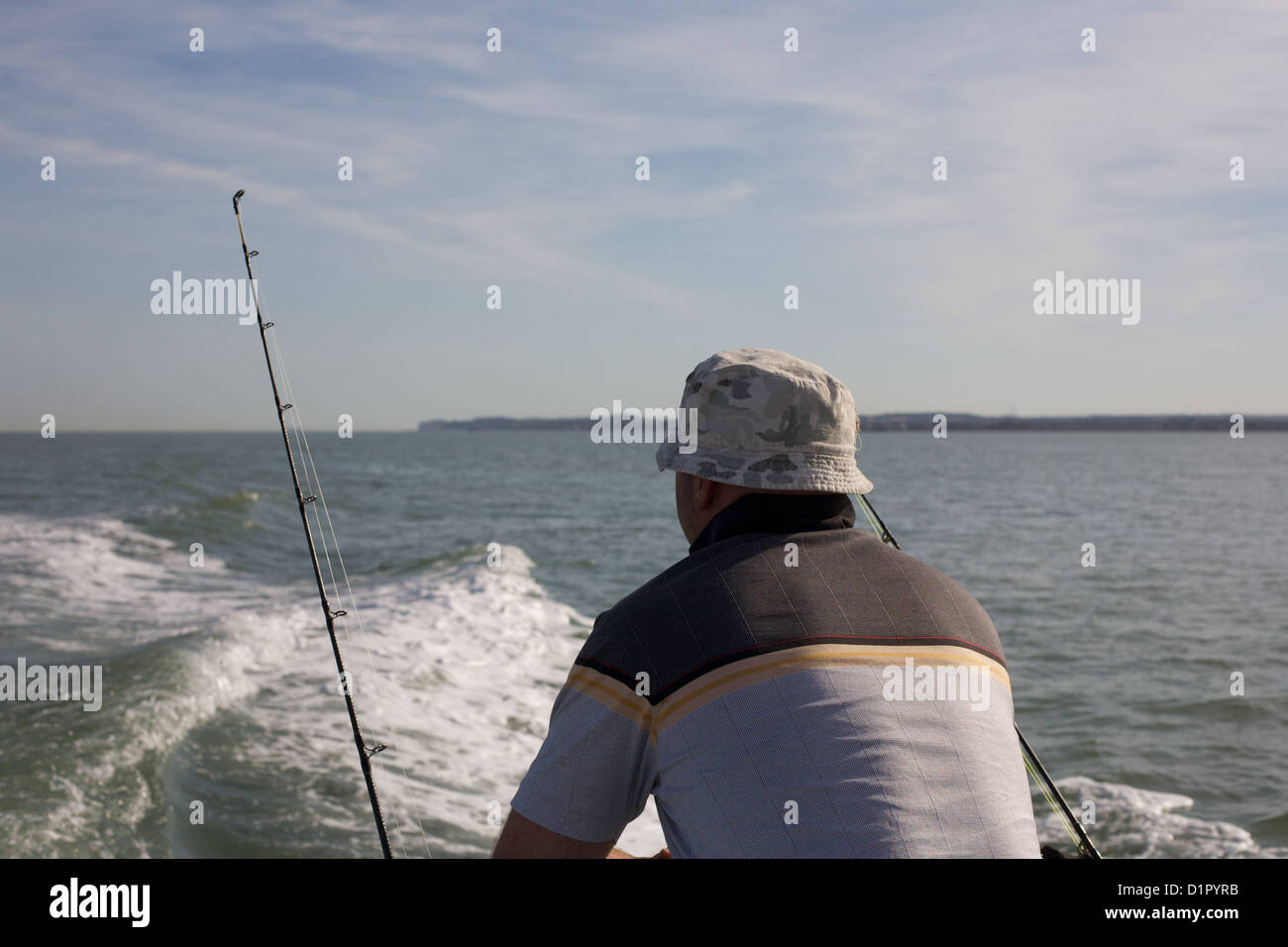 Man fishing for sea bass with rod and line from boat in English Channel