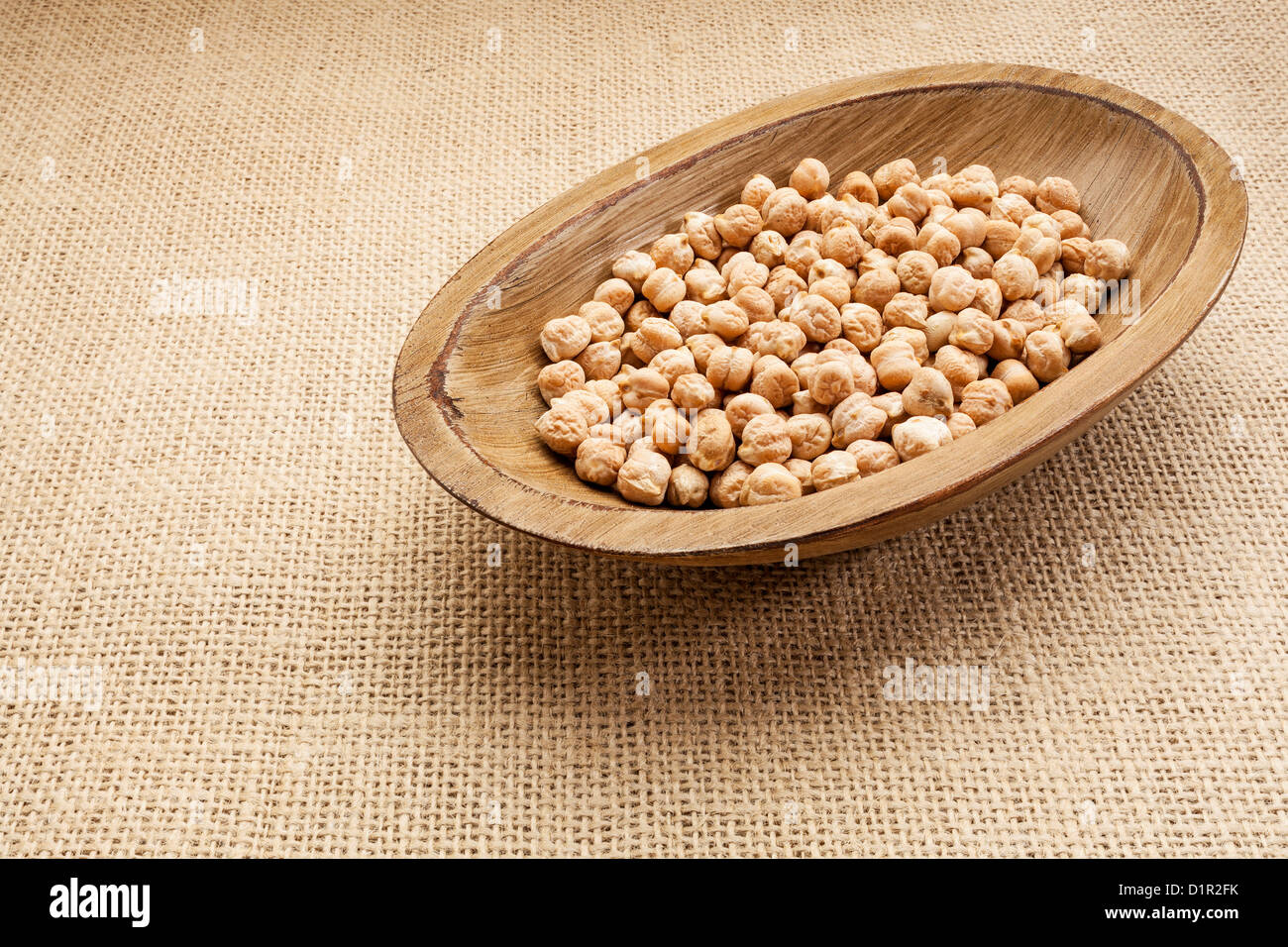 chickpea (garbanzo) beans in a rustic wood bowl against burlap canvas Stock Photo