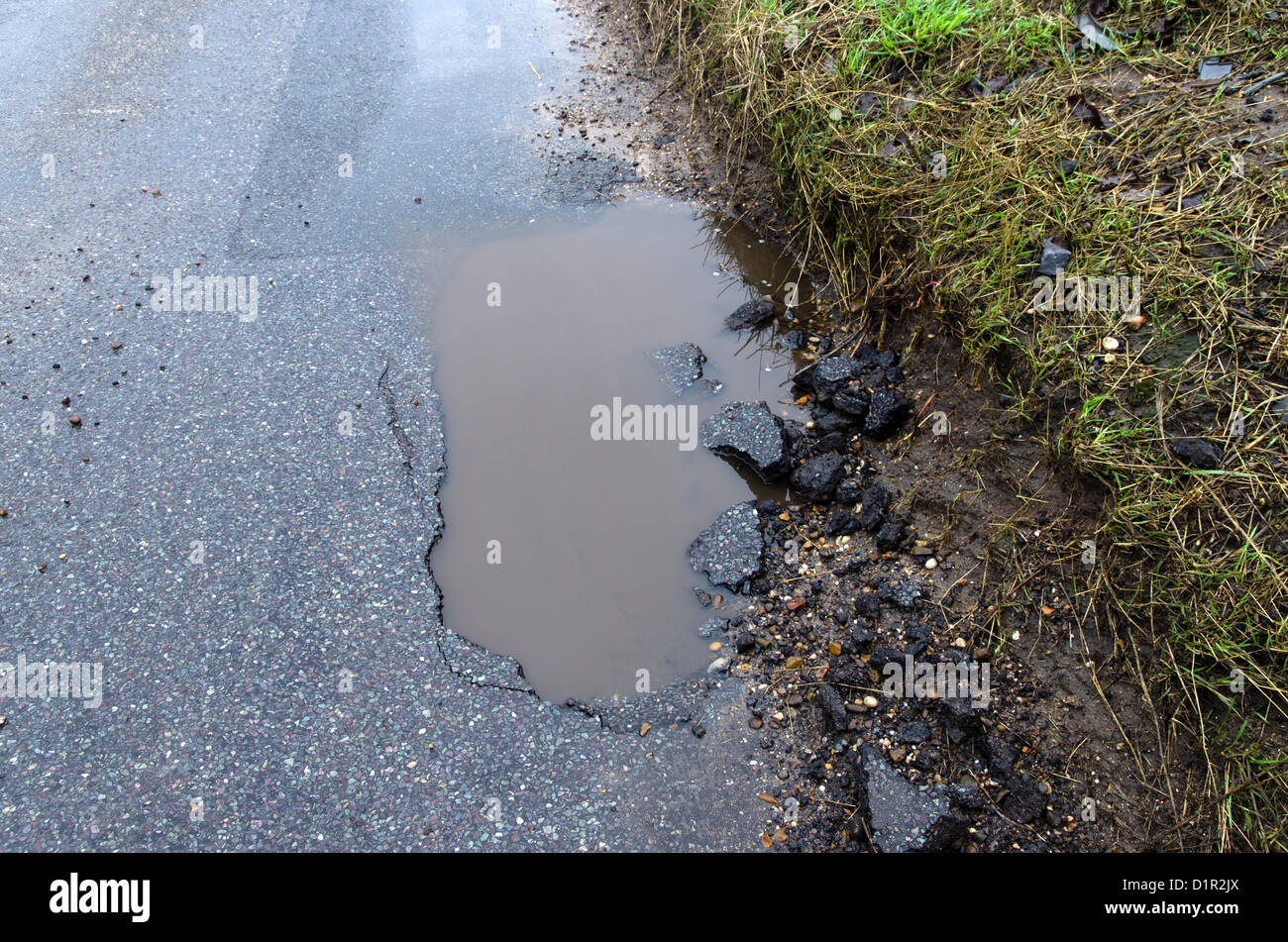 Great Bardfield, Essex. 2nd January 2013. Water from  recent heavy rain  fills a pot hole on Bell Lane Great Bardfield showing how the recent weather is damaging the road Stock Photo