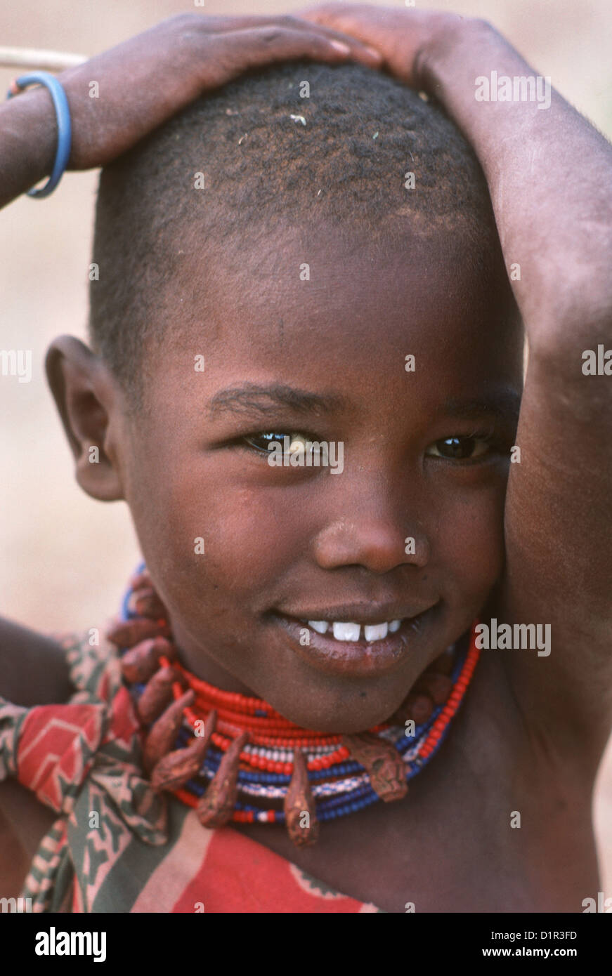 Kenya, Maasai girl child in traditional clothes looks straight at the