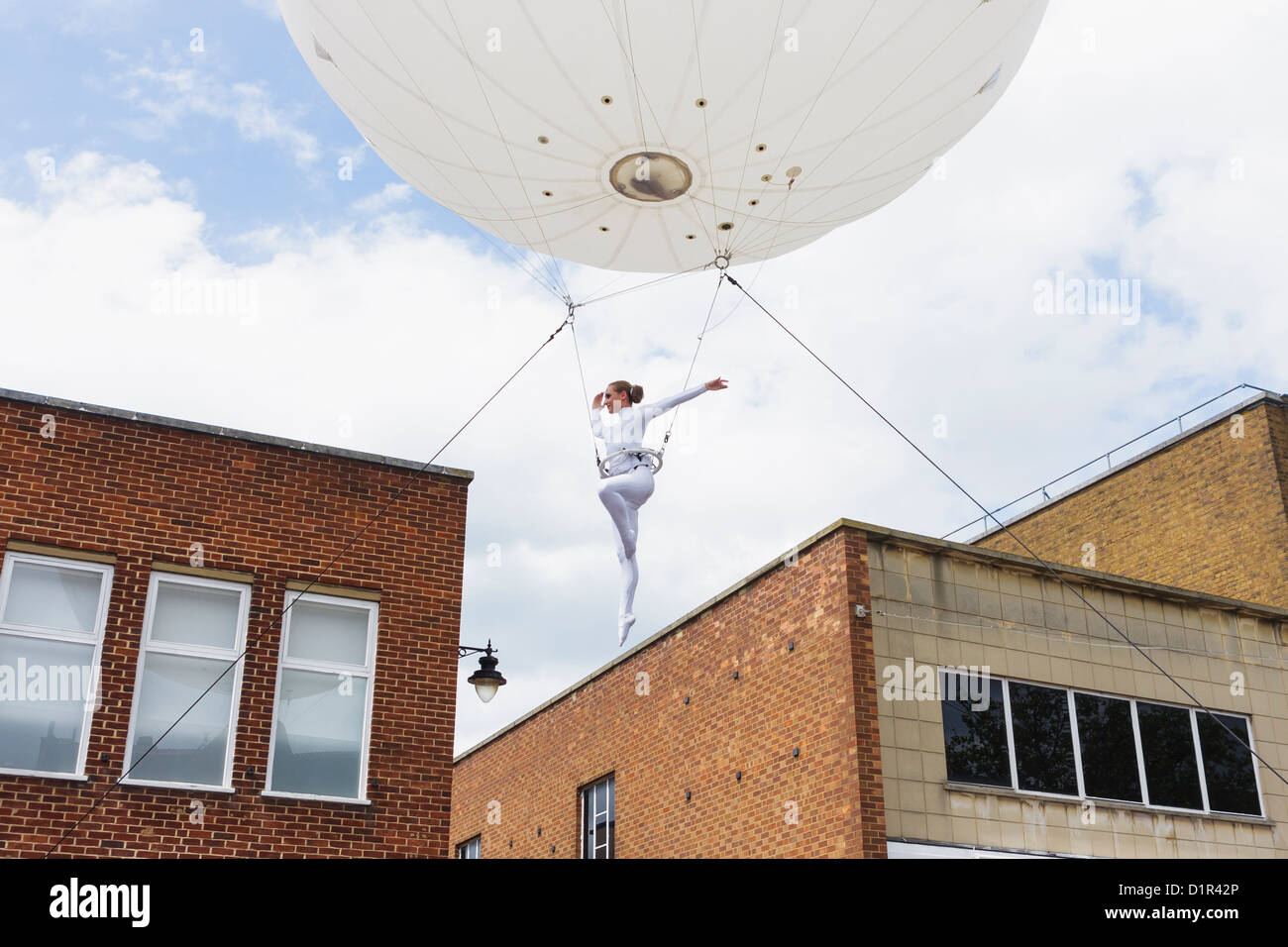 A trapeze artist is suspended from a large helium balloon during a Heliosphere performance. St Albans, UK 2012 Stock Photo