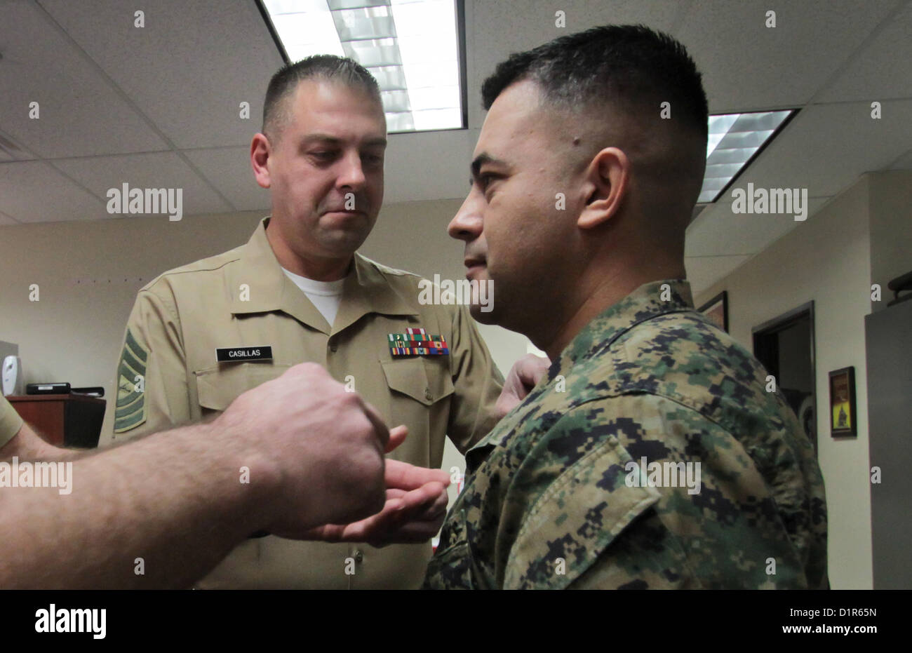 Gunnery Sgt. Roque Palmerinvega, right, receives new gunnery sergeant chevrons on his collar upon being promoted from staff sergeant to gunnery sergeant during a ceremony at the Marine Corps Recruiting Station Phoenix Headquarters in Phoenix, Jan. 2, 2013. Palmerinvega, a native of Myton, Utah, and a light armored vehicle crewman by trade, has been a recruiter in the Phoenix region since April, 2010. 'It's a big deal and a requires a much broader sense of leadership,' Maj. Steven M. Ford, commanding officer of R.S. Phoenix, said of Palmerinvega's promotion. 'It's a quintessential rank within t Stock Photo