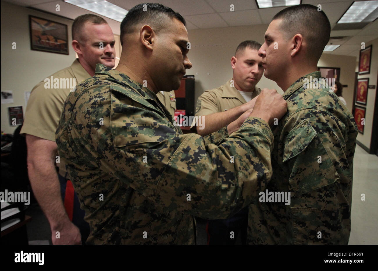Staff Sgt. Hector E. Orozco, receives new staff sergeant chevrons on his collar upon being meritoriously promoted from sergeant to staff sergeant during a ceremony at the Marine Corps Recruiting Station Phoenix Headquarters in Phoenix, Jan. 2, 2013. Orozco, a native of Los Angeles, and an aircraft electronic countermeasures systems technician by trade, has been a recruiter in the Phoenix region since July, 2011. 'To get promoted is one thing. Everybody out here on recruiting duty is hand selected and personally screened, so you're already dealing with an A-List group of people to begin with,'  Stock Photo