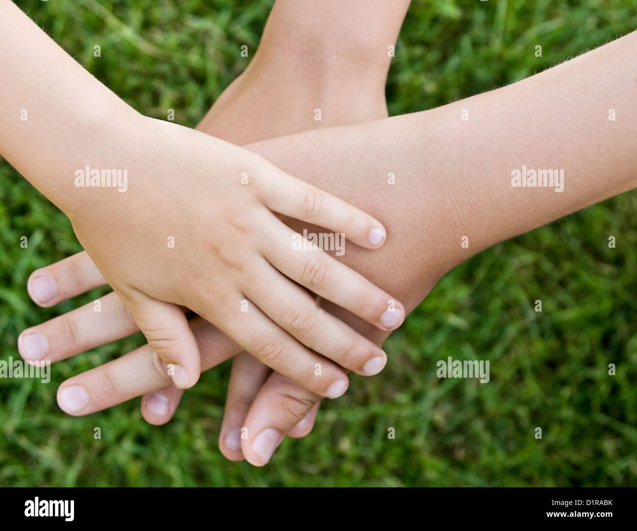 Children hand together over blurred (camera setup) grass background. Stock Photo