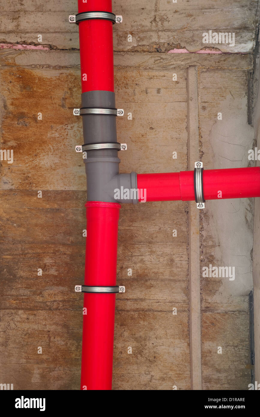 Red plastic water pipes against gray concrete wall Stock Photo Alamy