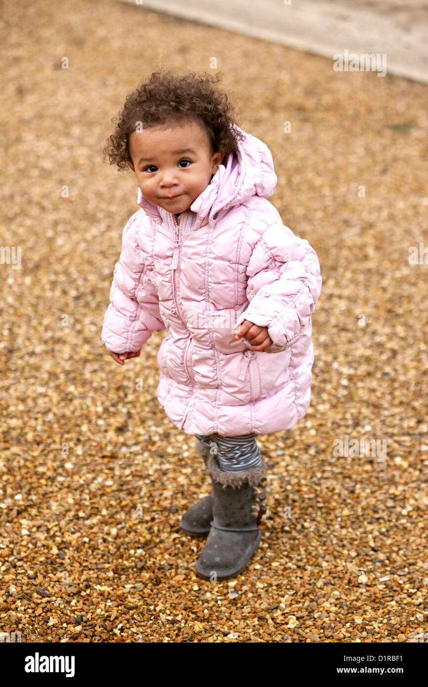 Outdoors portrait of cute happy toddler mixed race girl wearing a pink  coat,warm protective boots and leggings Stock Photo - Alamy