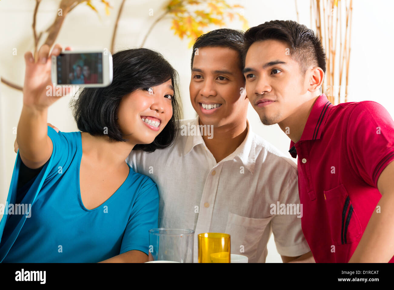 Asian friends, two men and a woman, having fun taking pictures with mobile phone Stock Photo