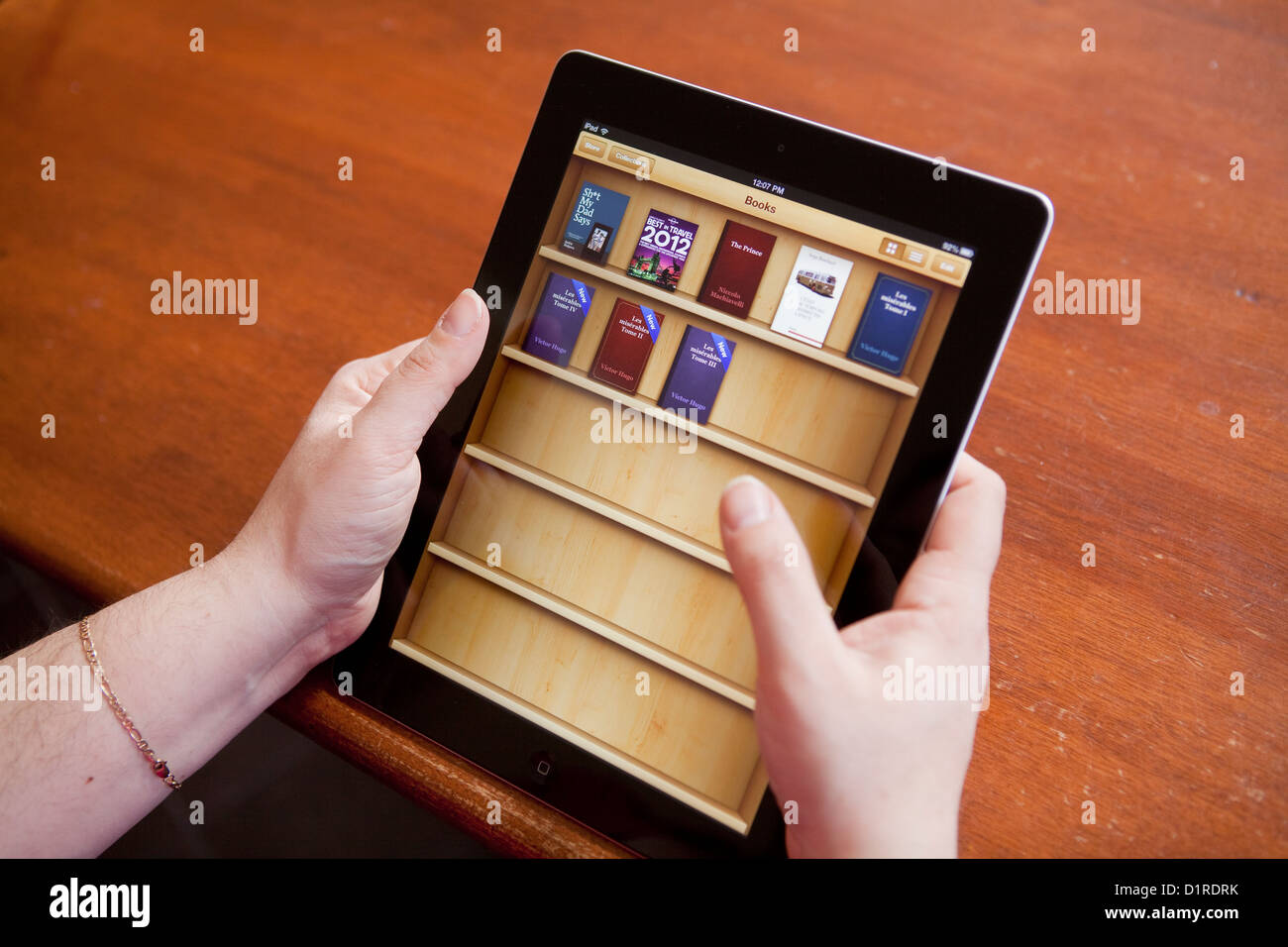 A woman turns the page of an ebook on the iPad 4 iBooks app Stock Photo