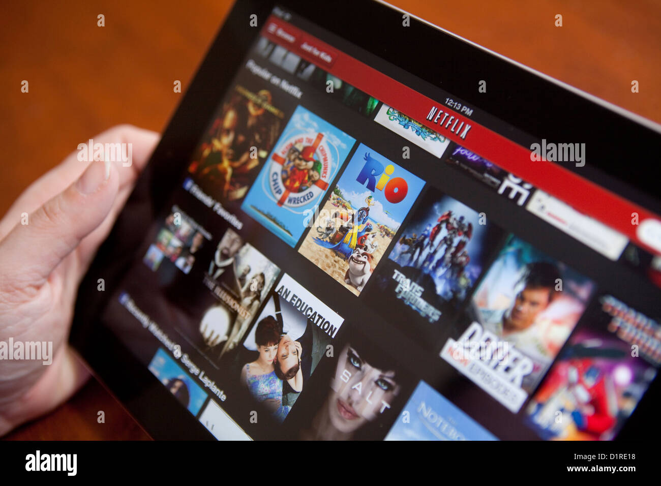 A woman uses the Netflix app on an iPad 4. Netflix, Inc. is an American provider of on-demand Internet streaming media. Stock Photo