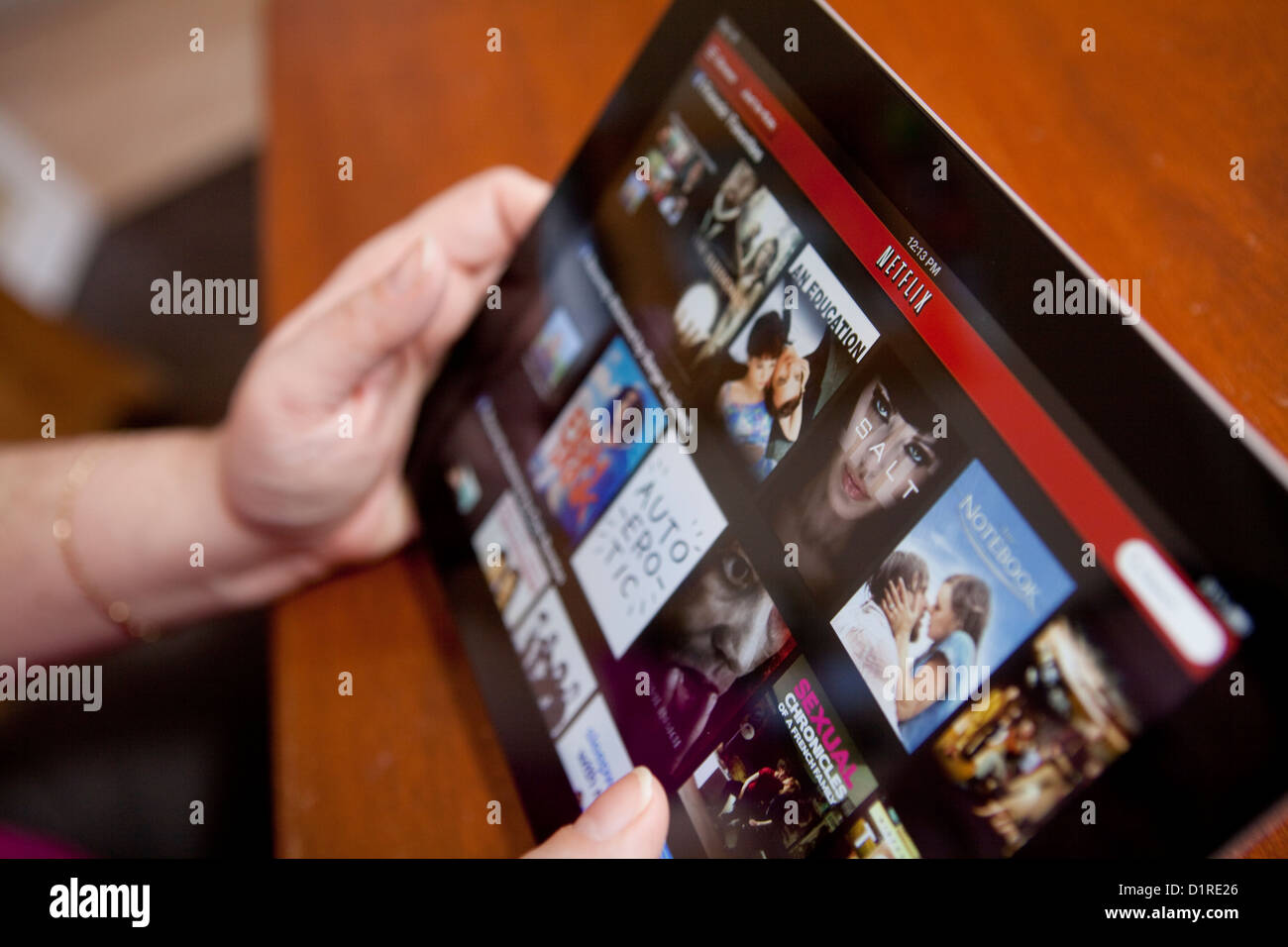 A woman uses the Netflix app on an iPad 4. Netflix, Inc. is an American provider of on-demand Internet streaming media. Stock Photo