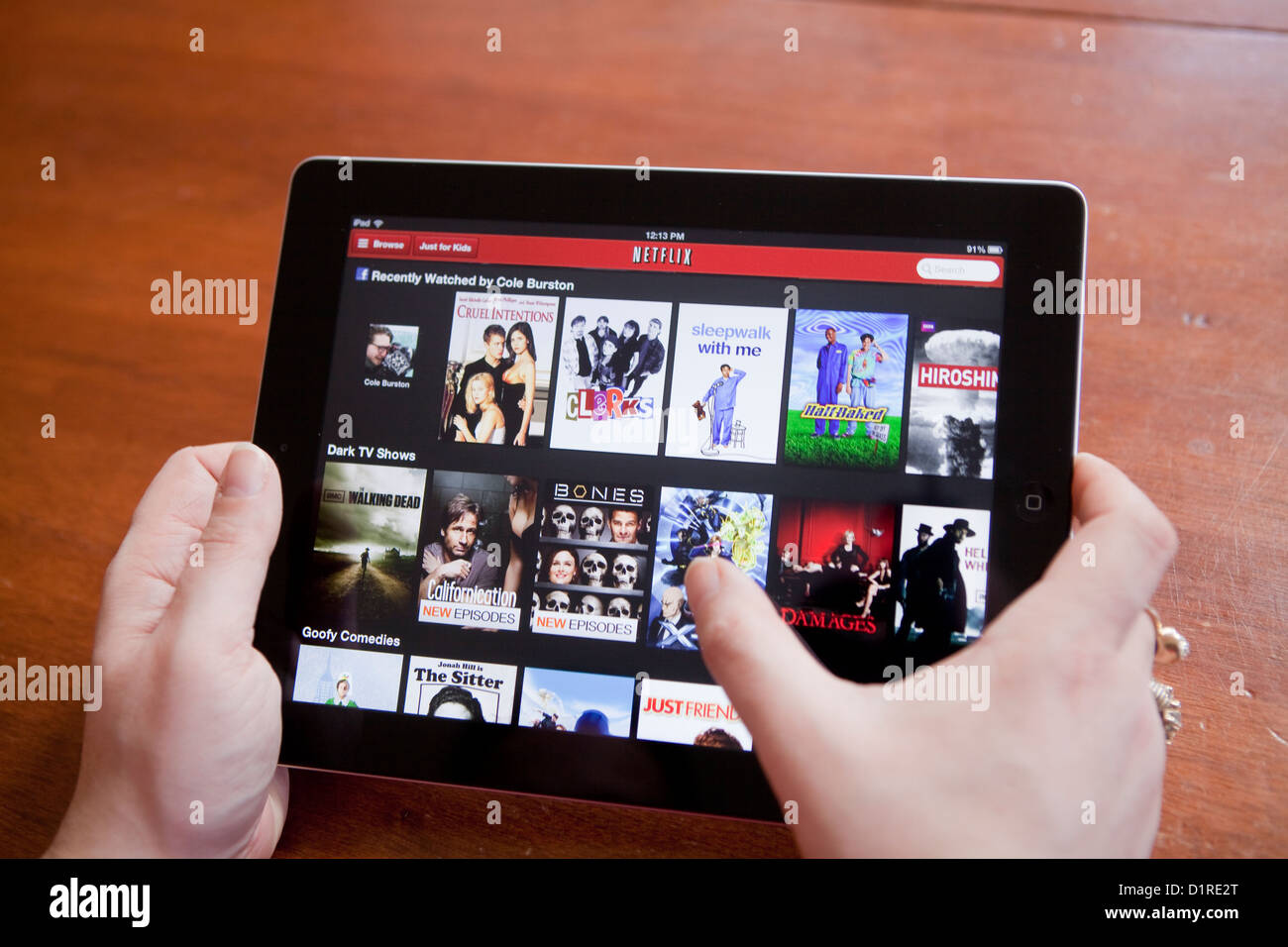 A woman uses the Netflix app on an iPad 4. Netflix, Inc. is an American provider of on-demand Internet streaming media. Stock Photo