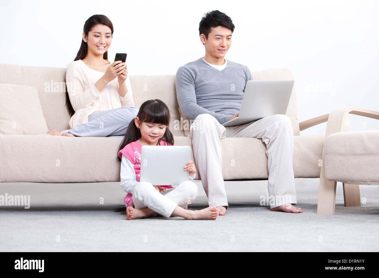 Young family using electronic gadgets in living room Stock Photo Alamy