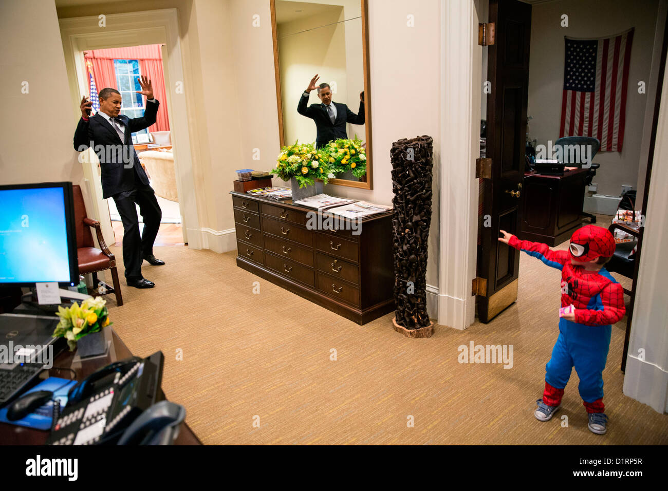 US President Barack Obama reacts as Spider-Man catches him in his web as he greets Nicholas Tamarin, 3, just outside the Oval Office during early Halloween trick-or-treating for White House Staff October 26, 2012 in Washington, DC. Stock Photo