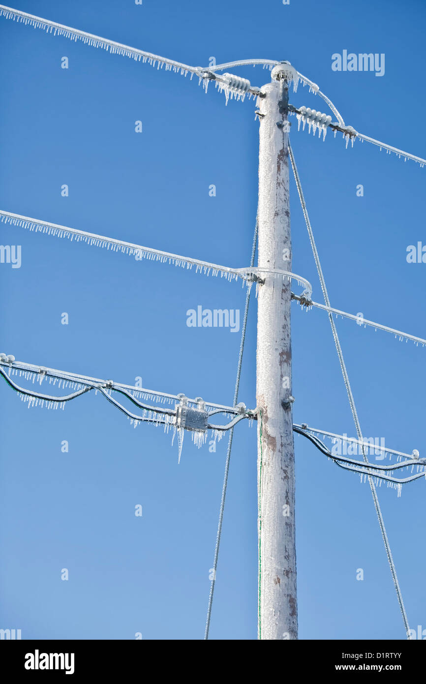 Power pole and lines covered in ice and icicles. Stock Photo