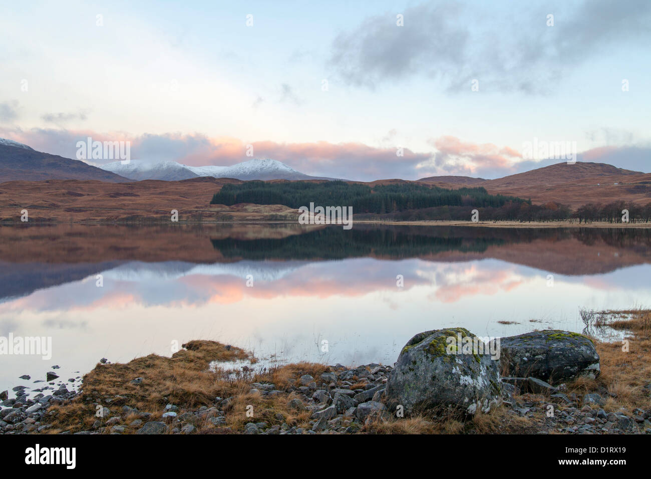 Loch Tulla shoreline and reflections of pink tinged clouds at sunrise Scotland Stock Photo