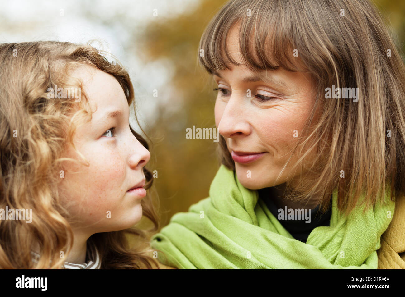 Mother and teenager daughter looking at each other while walking in an autumn park Stock Photo