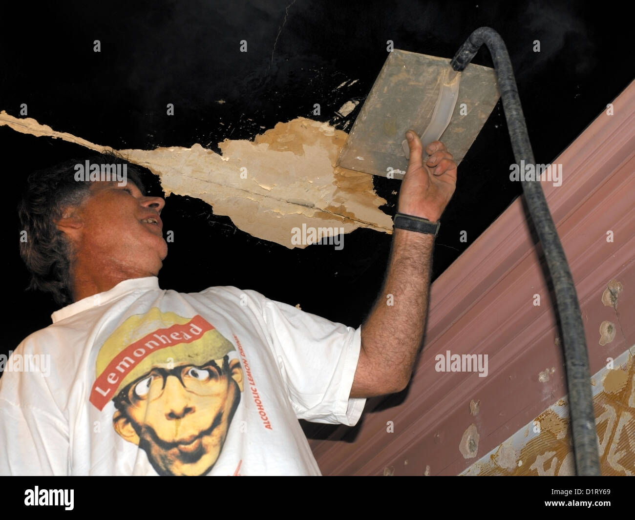 Man Using Steamer on Ceiling and Wearing T-Shirt with Lemonhead Stock Photo
