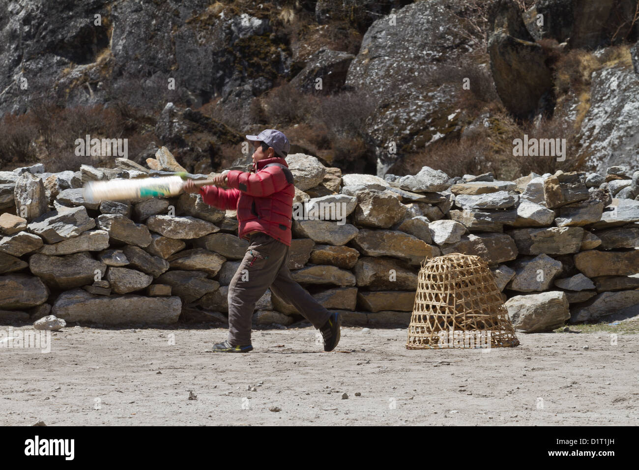 A young boy playing cricket with a improvised wicket in a Nepalese village,in the Khumbu Valley Nepal, Asia Stock Photo