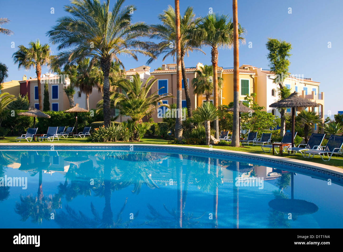 Colònia de Sant Pere, Mallorca, Balearic Islands, Spain. View across pool to luxury apartment complex set amongst palm-trees. Stock Photo