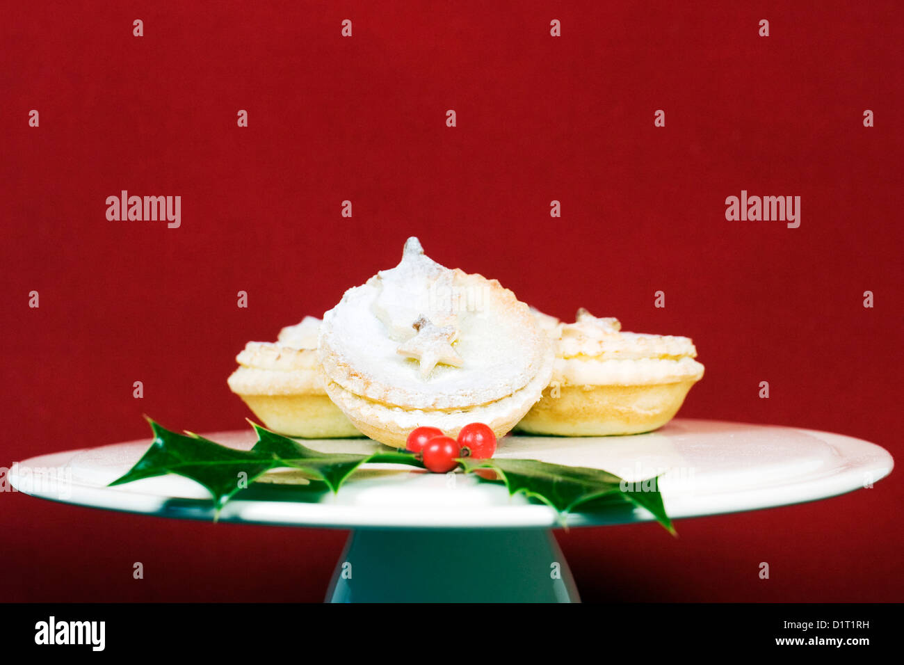 Freshly made mince pies on a cake stand against a red background. Stock Photo