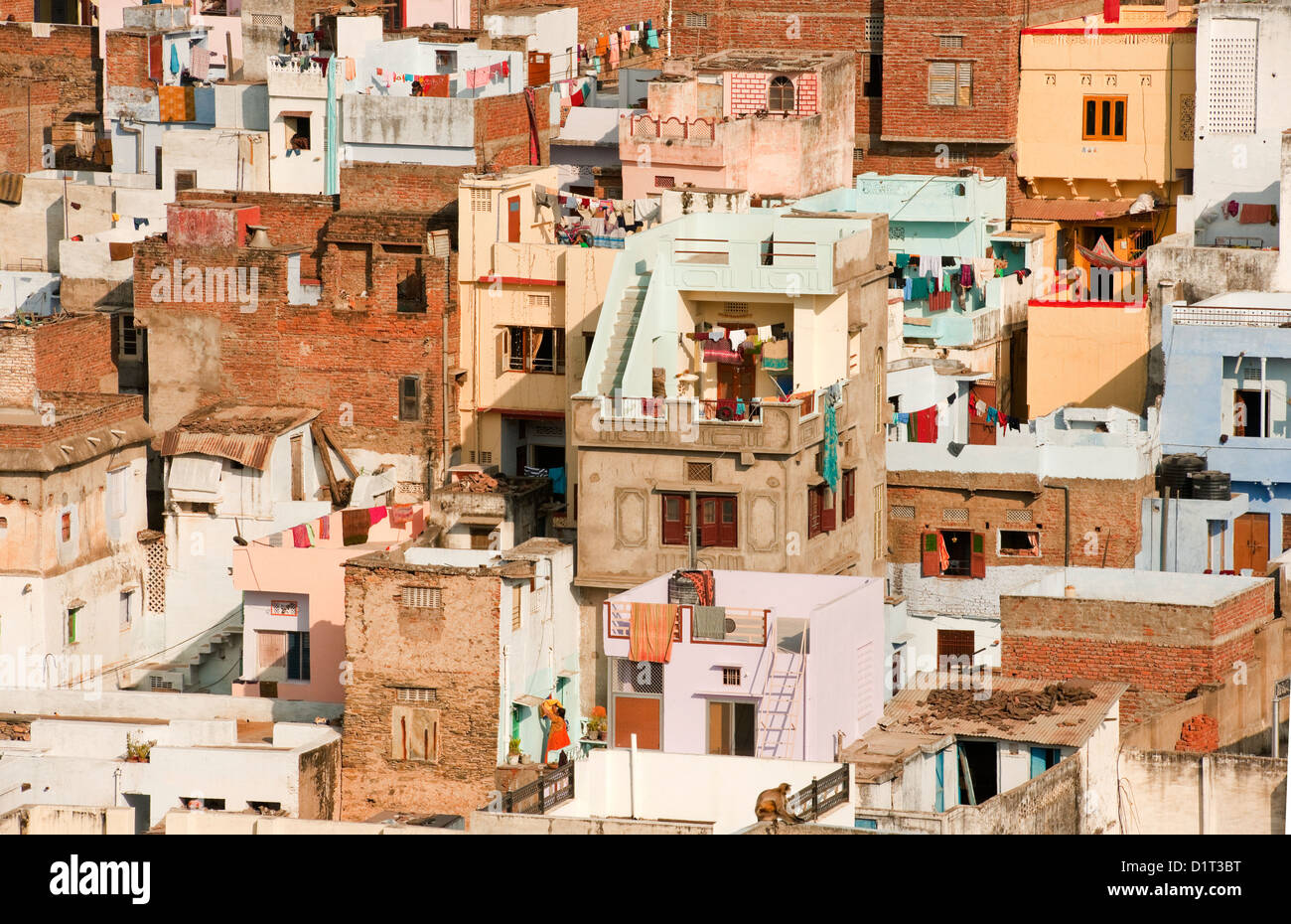 A view of the colorful rooftops of Udaipur Rajasthan India with some people and washing lines and geometric shapes of buildings Stock Photo