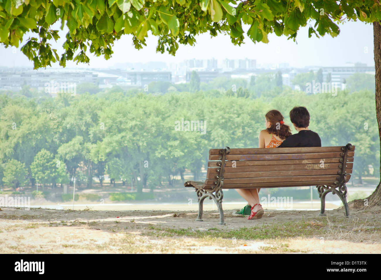 Couple in love sitting on a park bench and enjoy the view ...