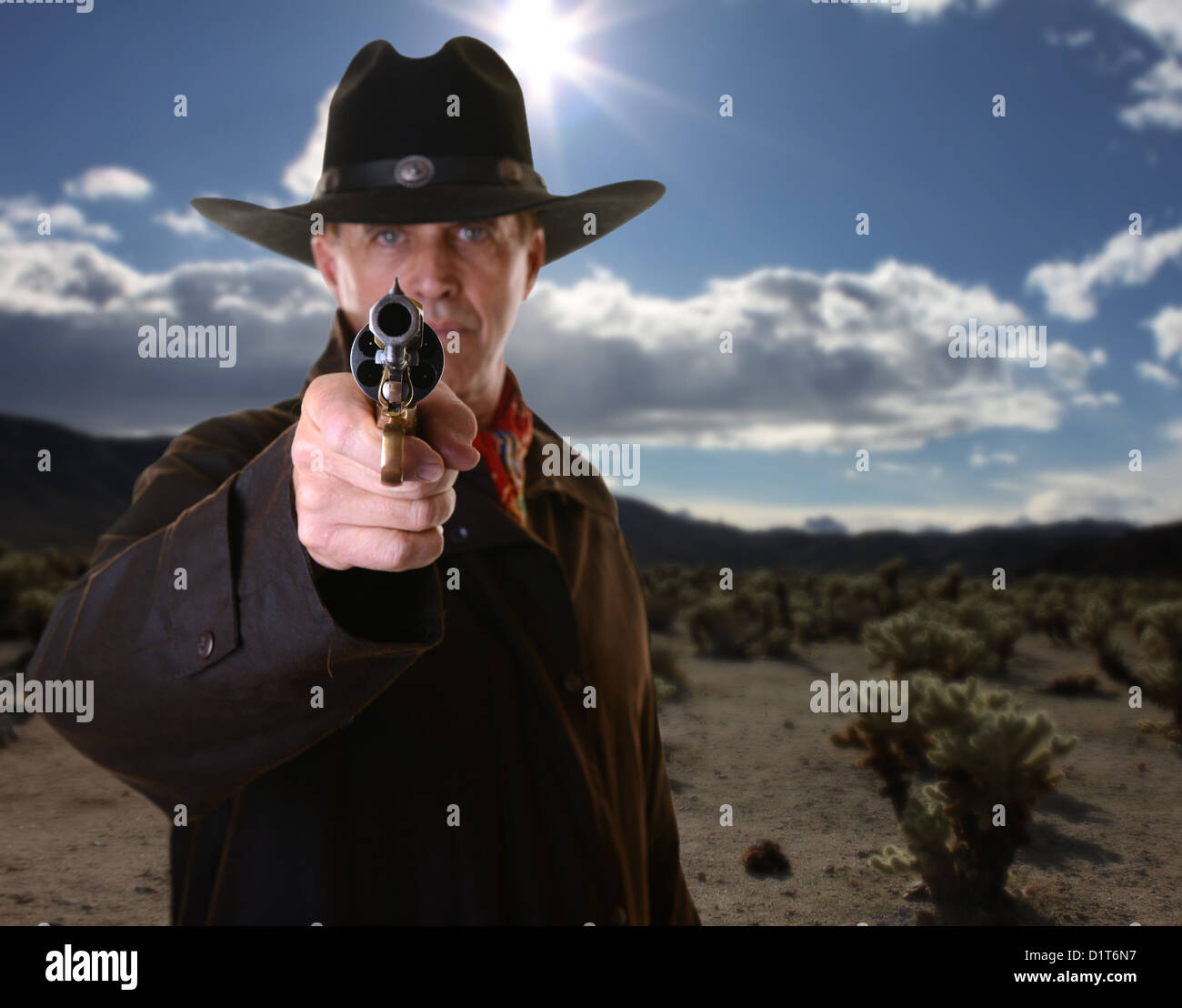 Cowboy pointing gun with selective focus on gun against desert
