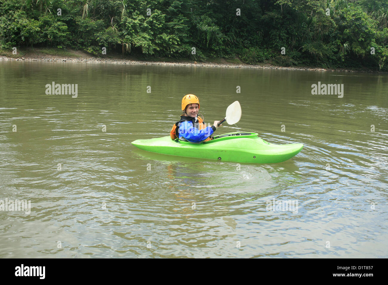 A male teenager paddling a kayak down the Napo River in the Ecuadorian rain forest near Tena, Ecuador Stock Photo
