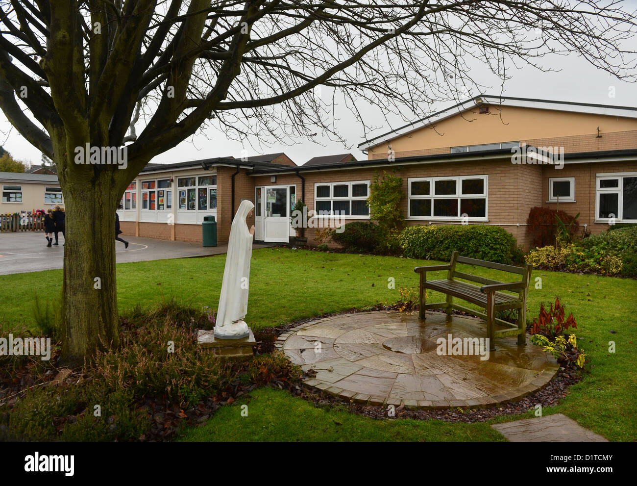 A sitting area and statue of the Madonna on a wet day at Our Lady & St. Werburgh's Catholic Primary School in Newcastle-under-Ly Stock Photo