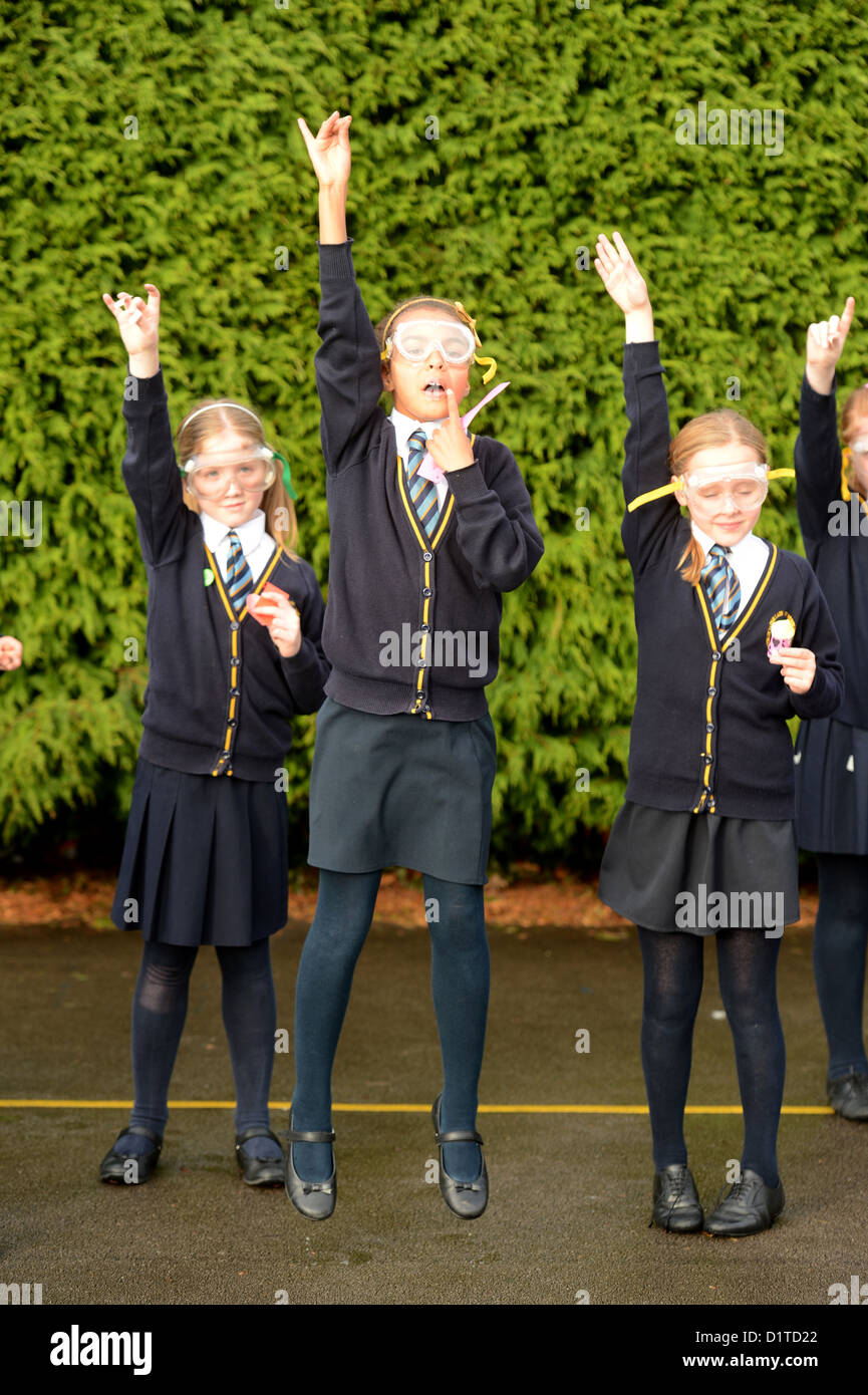 School girls with their hands up during an outdoor rocket launch science lesson at Our Lady & St. Werburgh's Catholic Primary Sc Stock Photo
