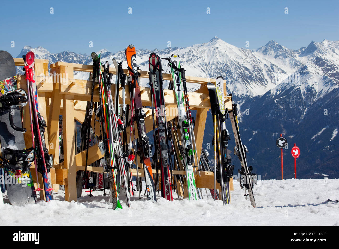 A row of colourful skies sits outside of a mountain top chalet awaiting their owners. Stock Photo