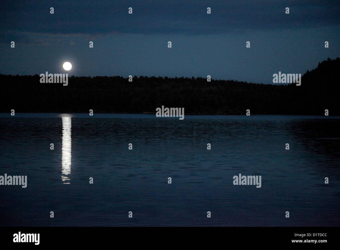 Evening land and water scape of the moon rising over the Ottawa River, in Ontario Canada. Stock Photo