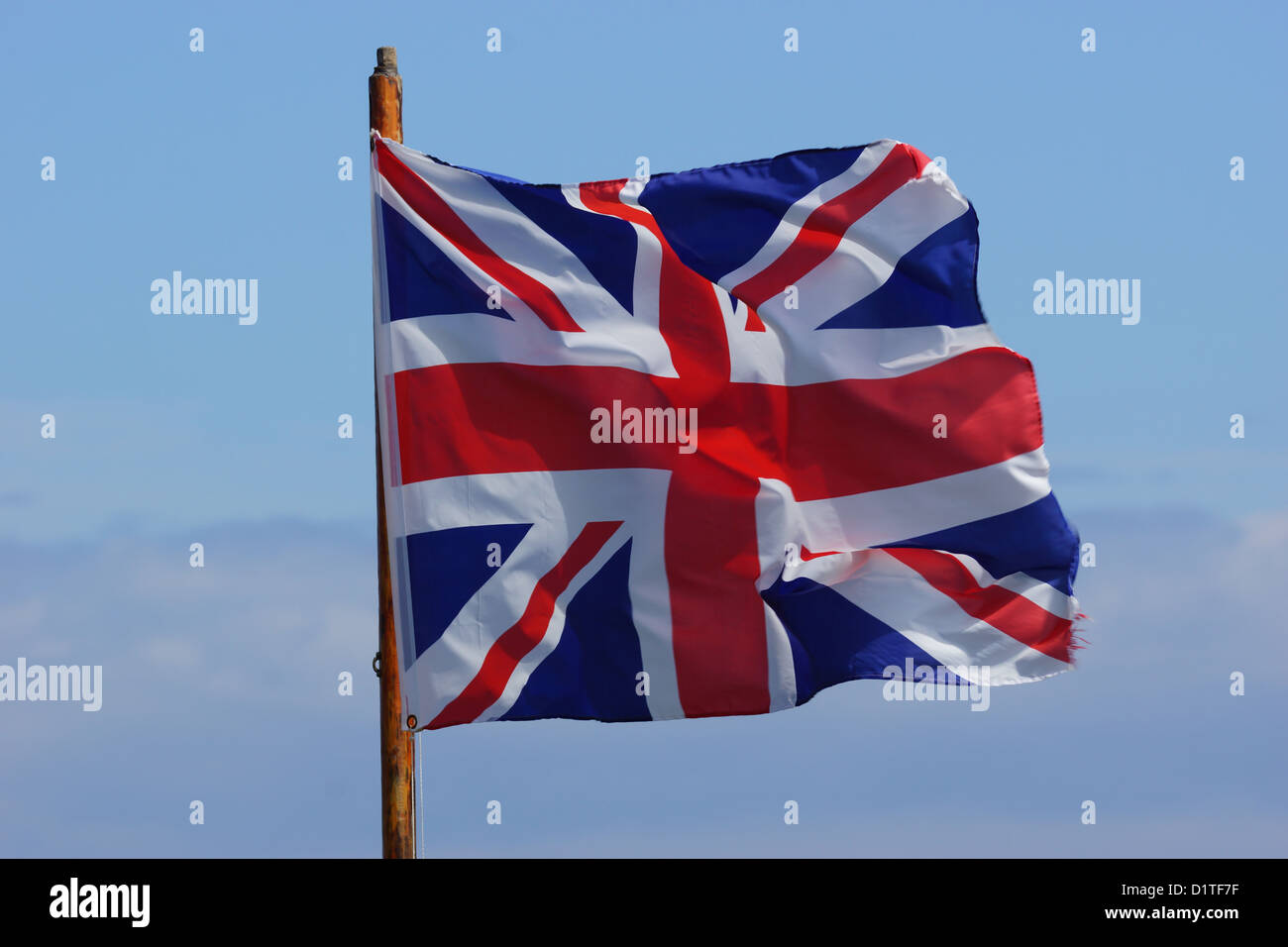 British Flag / Union Jack blowing in the wind against a blue sky Stock Photo