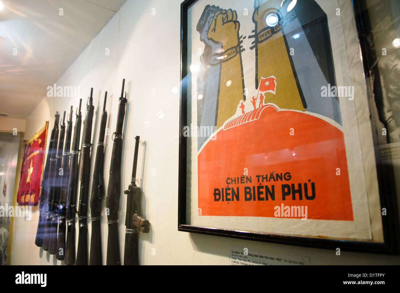 HANOI, Vietnam - At right is a propaganda poster celebrating the Vietnamese victory over the French in 1954 at Dien Bien Phu. At left are weapons used in the battle. The Museum of the Vietnamese Revolution in the Tong Dan area of Hanoi, not far from Hoan Kiem Lake, was established in 1959 and is devoted to the history of the socialist revolutionary movement in Vietnam. Stock Photo
