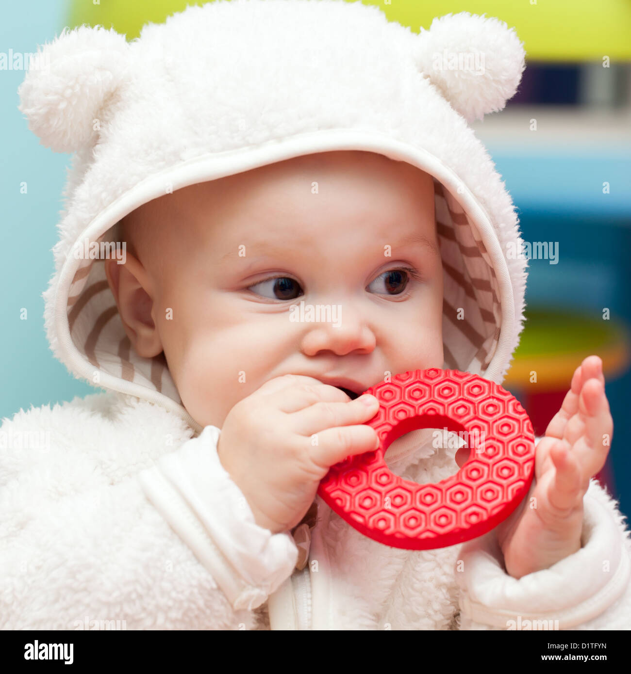 little baby chews on a soft plastic toy in white bear costume Stock Photo
