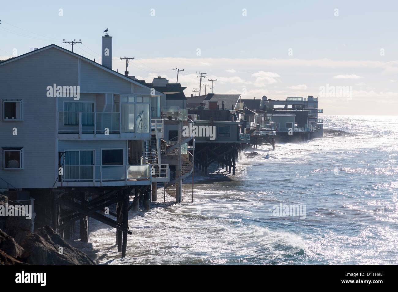 Modern houses overhang ocean and waves in Malibu California Stock Photo
