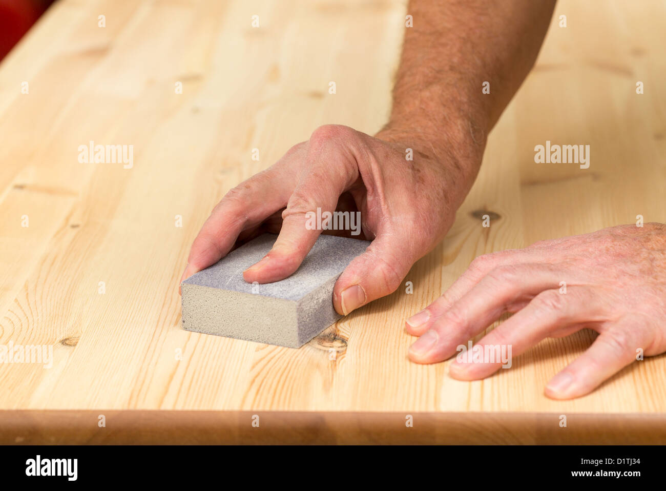 Man holding sanding block on pine floor or table sanding surface Stock Photo
