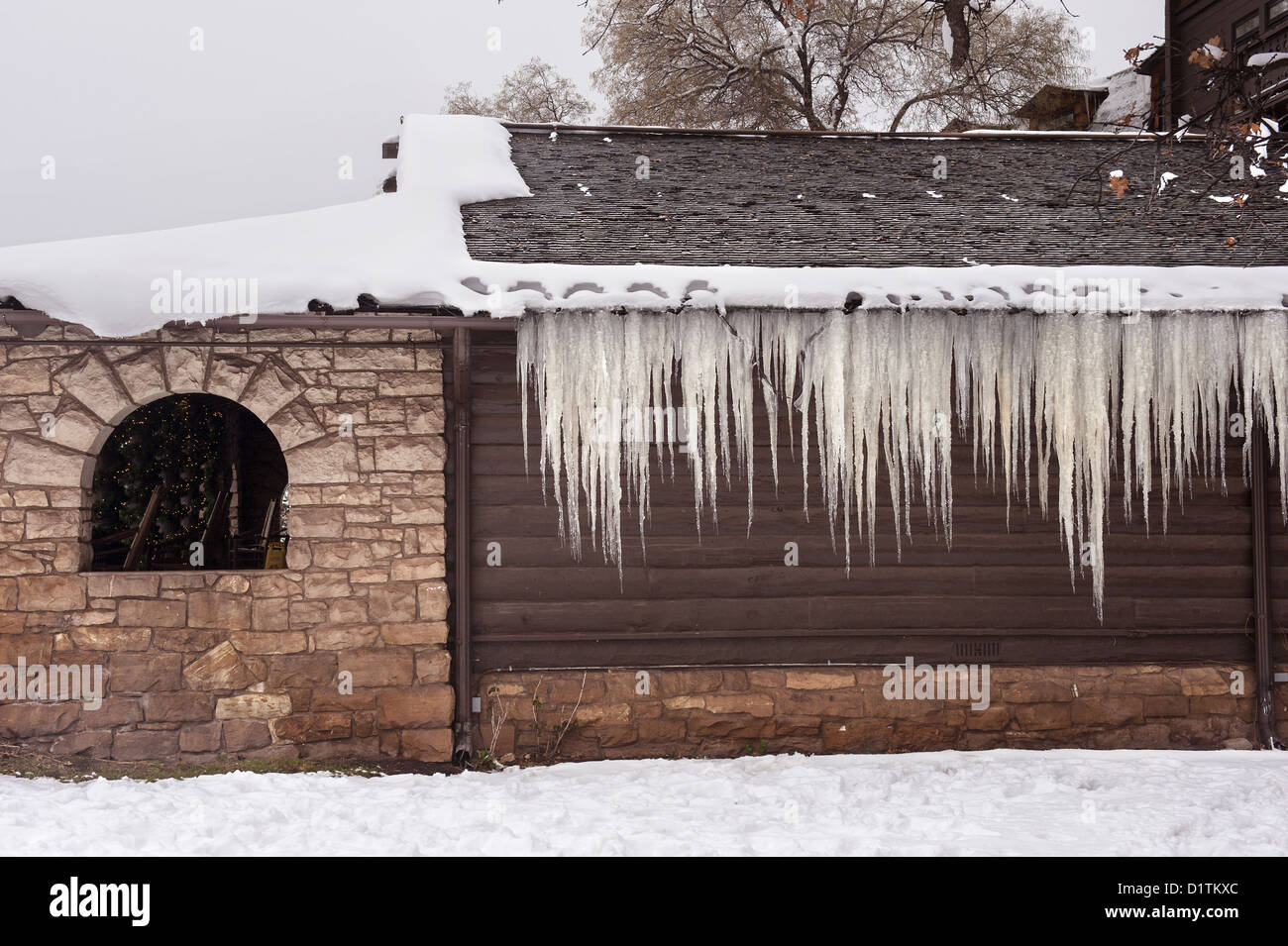 A mountain chalet lodge exterior covered in snow and icicles shows an idyllic winter vacation destination. Stock Photo