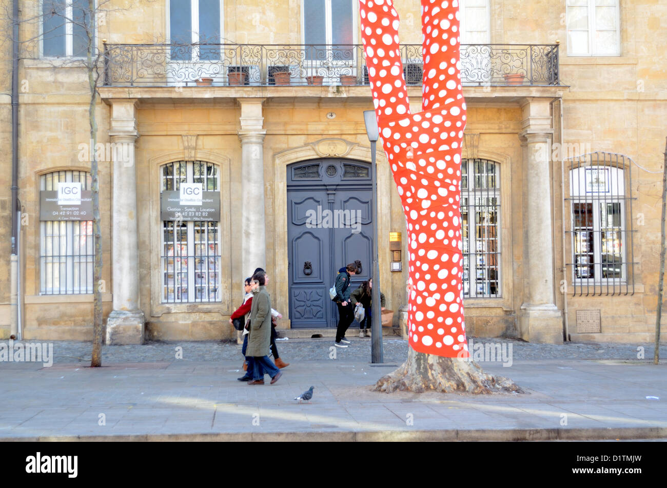 Pedestrians Walk Past a Hotel Particulier or Bourgeois Town House and Wrapped Plane Tree Decorated in Red & White Polka Dot Paper by Japanese Artist Yayoi Kusama Cours Mirabeau Aix-en-Provence for Inauguration of Marseille-Provence 2013 European Capital of Culture. Provence France Stock Photo
