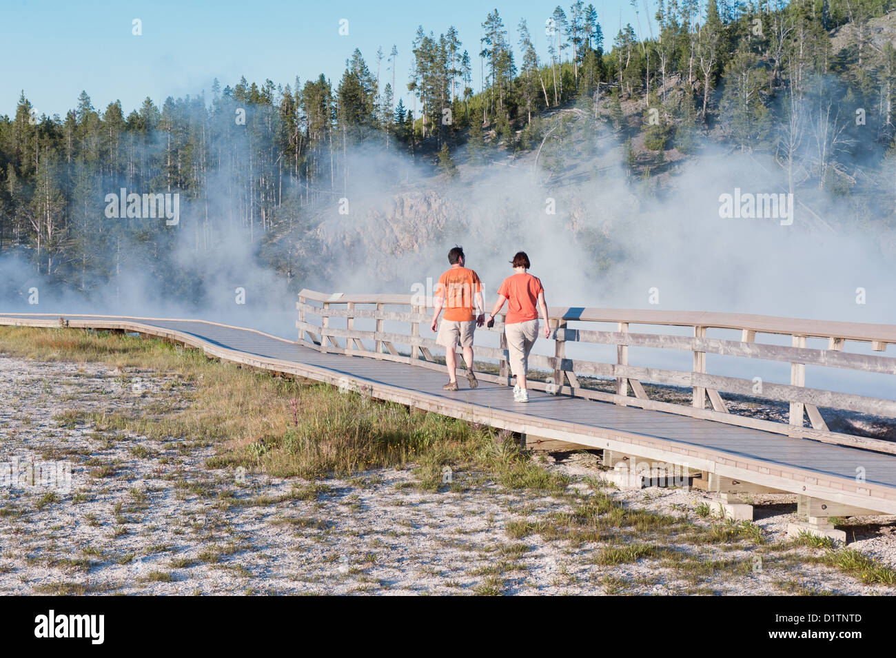 A couple walks by the Excelsior Geyser Crater, in Yellowstone National Park Stock Photo
