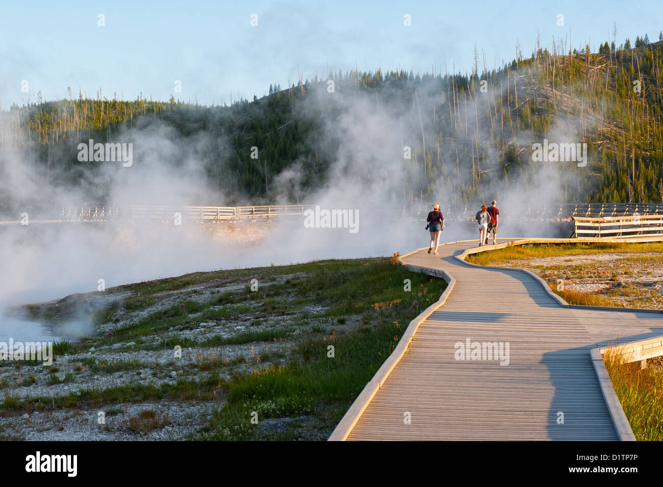 A group of people walk by the Excelsior Geyser, in Yellowstone National Park. Stock Photo