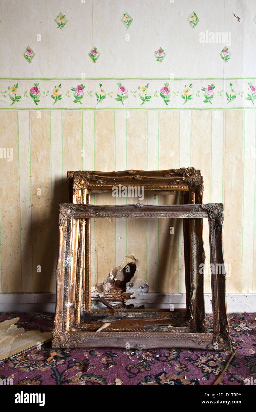 Three antique picture frames leaning against a wall with flowered
