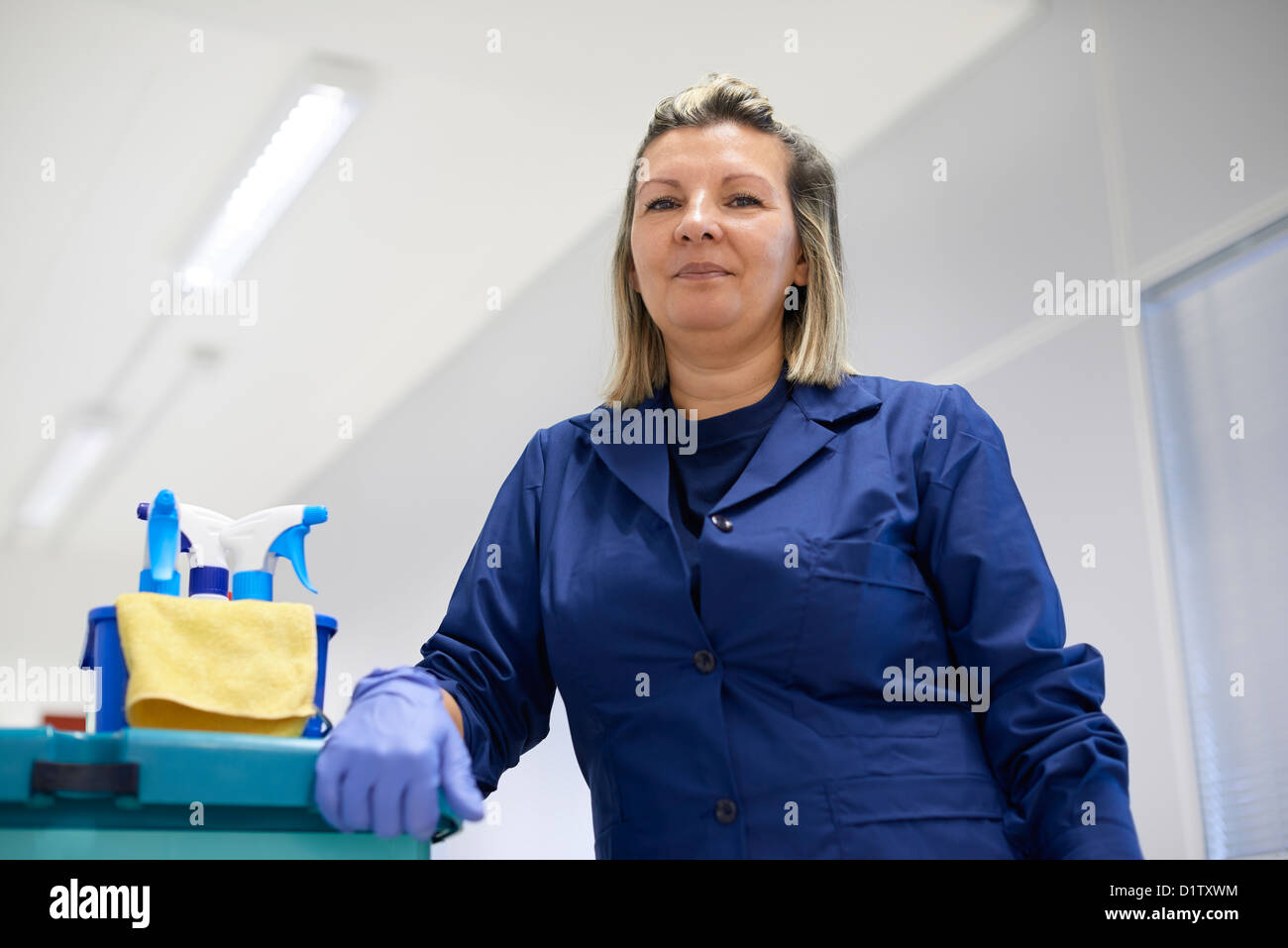 Women at work, portrait of happy professional female cleaner smiling and looking at camera in office. Low angle view Stock Photo