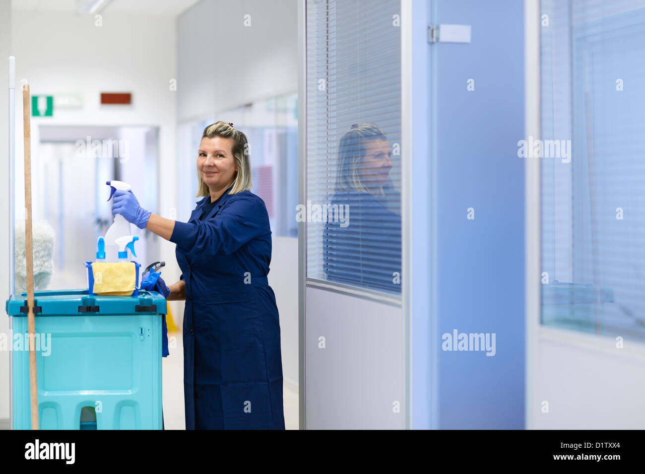 Women at work, portrait of happy professional female cleaner smiling and looking at camera in office. Three quarter length Stock Photo