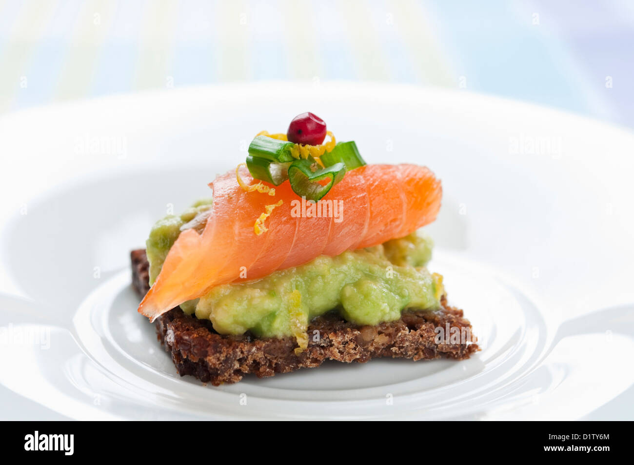 Brown bread sandwich with smoked salmon, avocado topped with chive and pepper Stock Photo