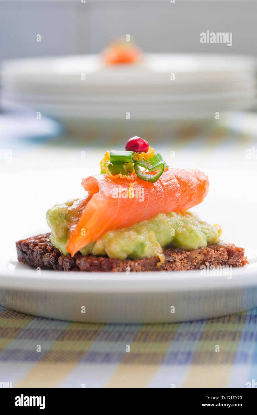 Brown bread sandwich with smoked salmon, avocado topped with chive and pepper Stock Photo