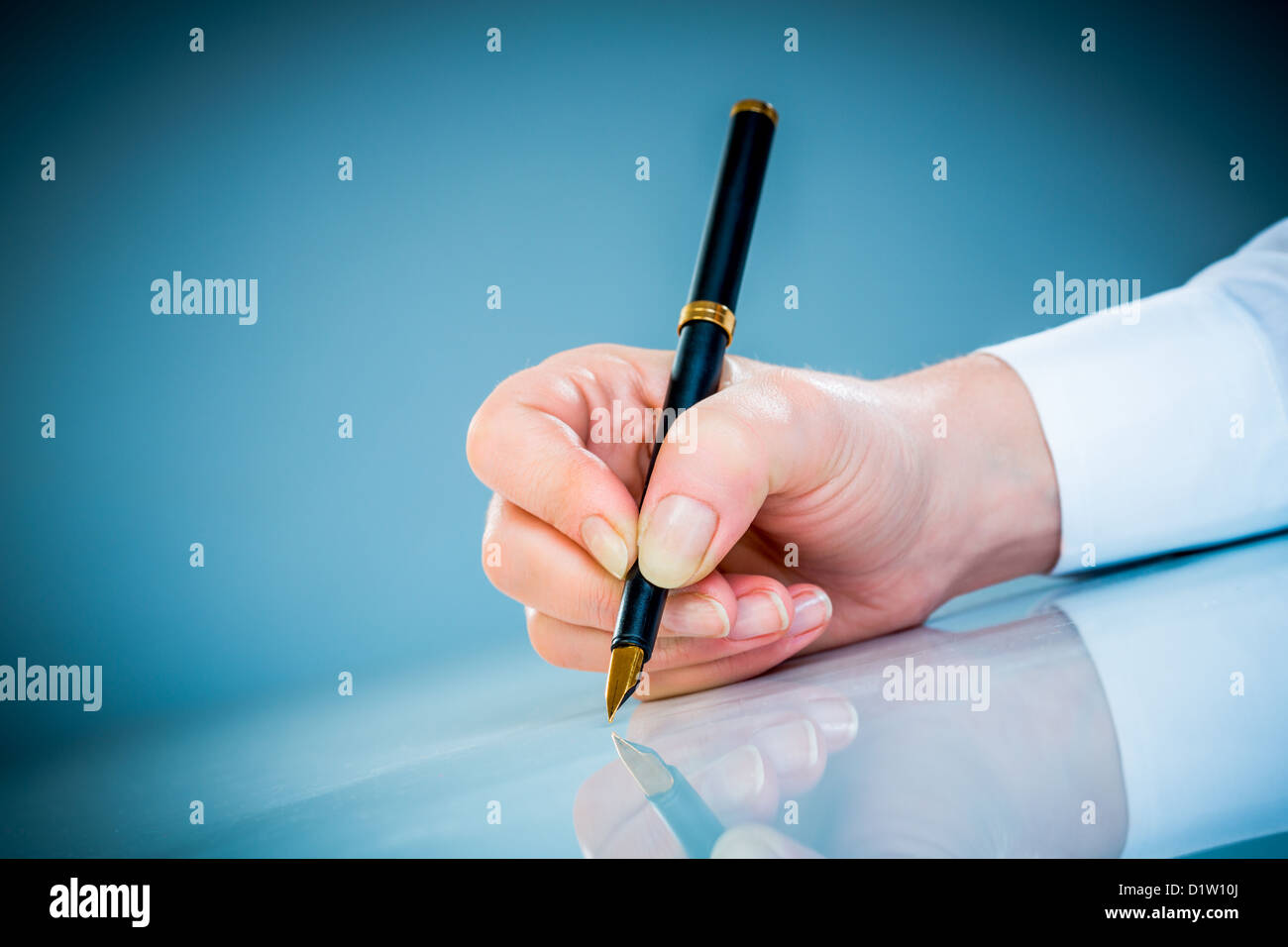 Woman's hand with a pen on a blue background Stock Photo